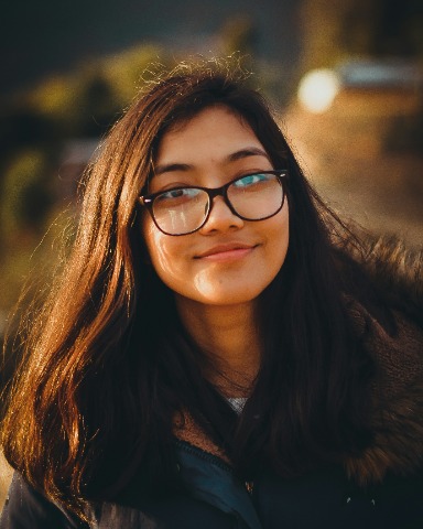 Eine junge Frau mit Brille, die freundlich in die Kamera schaut